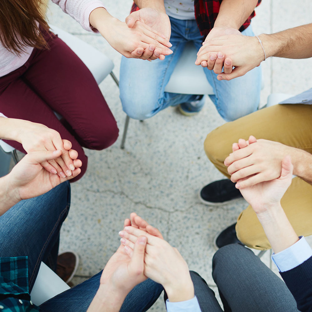 Above shot of group of students praying and holding hands